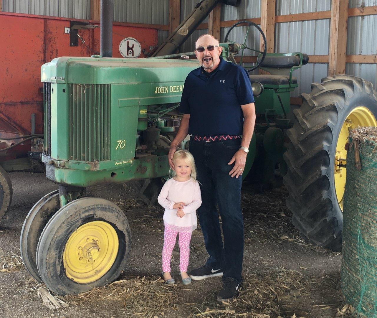 Steve Cherney with a child beside a John Deere tractor